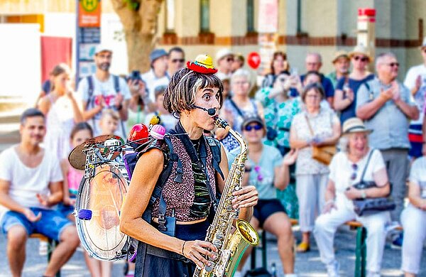 Eine Straßenkünstlerin spielt Trompete vor Publikum