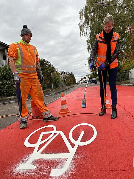 Oberbürgermeisterin Katrin Albsteiger markiert die neue Fahrradstraße mit einem Radsymbol.