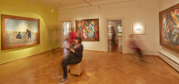 Austellungsraum mit Gemälden und Besuchern