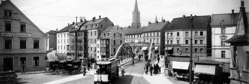 Altes Schwarz-Weiß-Foto von der Neu-Ulmer Innenstadt mit Straßenbahn, im Hintergrund das Neu-Ulmer Münster