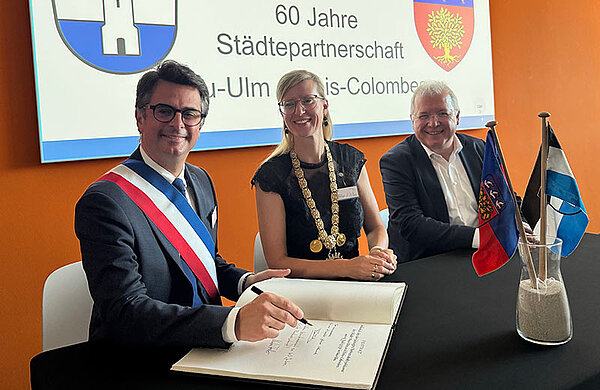 Der Bürgermeister von Bois-Colombes trägt sich ins goldene Buch ein, neben ihm Oberbürgermeisterin Katrin Albsteiger und Markus Ferber.