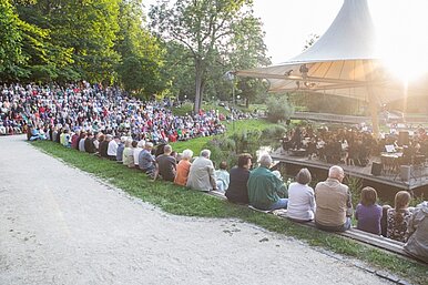 Veranstaltungsbühne im Stadtpark mit Orchester und Besuchern des Openair-Konzertes