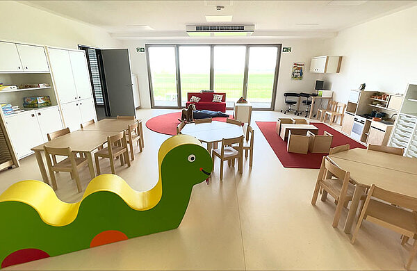 Gruppenraum in der Kita mit Möbeln und einer großen bunten Schlange zum Sitzen und Spielen.