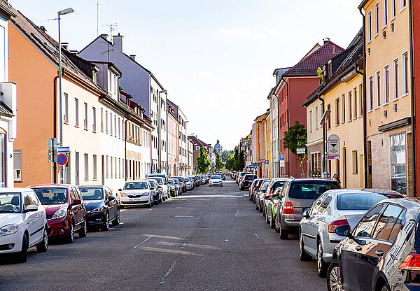 Straße in der Innenstadt mit Wohnhäusern und parkenden Autos