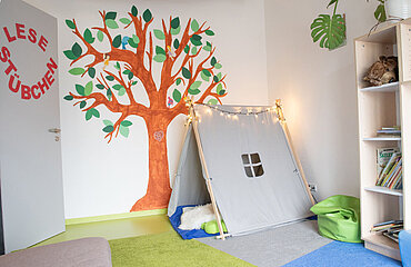 Kita-Raum mit Tippi-Zelt, Regal mit Büchern; an der Türe die Beschriftung "Lesestübchen"