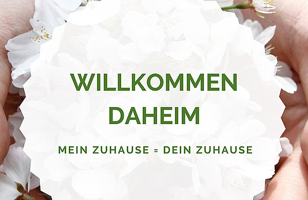 Schriftzug Willkommen daheim auf Blüten-Hintergrund