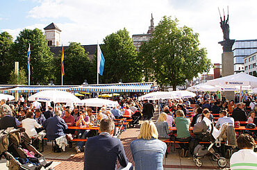 Stadtfest-Besucher sitzen an Biertischen auf dem Rathausplatz