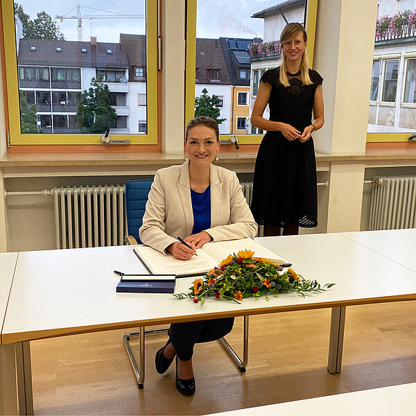 Bayerns Digitalministerin Judith Gerlach beim Eintrag ins Goldene Buch, hinter ihr stehend Oberbürgermeisterin Katrin Albsteiger