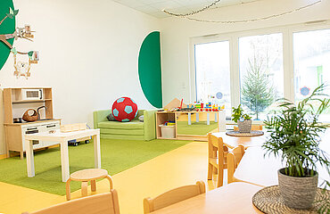Raum im Kinderhaus Bärenhöhle mit Tischen, Stühlen und Spielemöglichkeiten