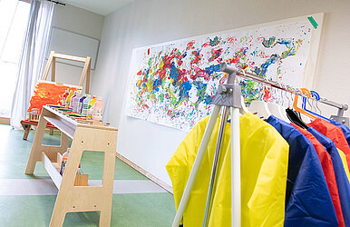 Atelier mit Leinwand, Farben, Malbekleidung und bunt angemalter Leinwand