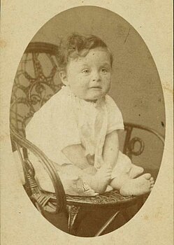 Alfred Neuburger als kleines Kind auf einem Stuhl sitzend