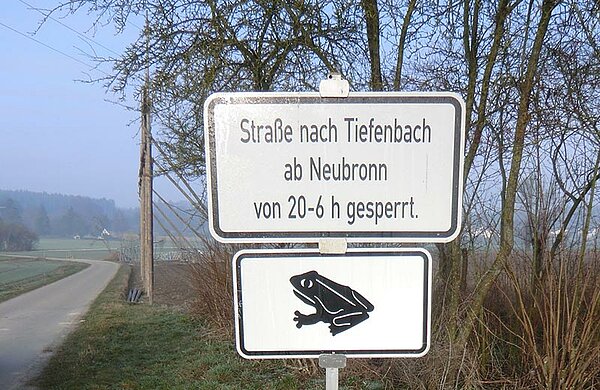 Neben einer Landstraße weist ein Schild auf die nächtliche Sperrung wegen der Krötenwanderung hin.
