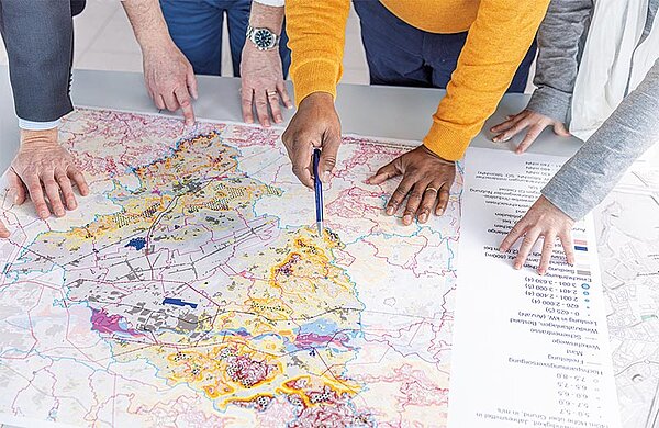 Mehrere Personen schauen in einen Stadtplan.