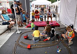 Kinder spielen an einer Spielstation mit Eisenbahn und Bauklötzen