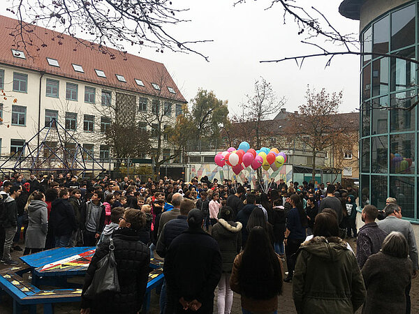 Der Pausenhof der Peter-Schöllhorn-Schule voller Schülerinnen und Schüler, im Hintergrund mit Helium gefüllte Luftballons