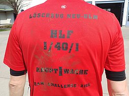 Rückansicht des roten Teilnehmershirts mit dem Text "Löschzug Neu-Ulm Hauptwache Team - Challenge - Ziel"