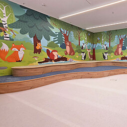 Kinderbereich mit bunt bemalter Wand mit Waldtieren