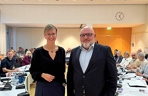 Die Neu-Ulmer Oberbürgermeisterin steht neben dem frisch gewählten neuen Stadtkämmerer Gregor Kamp. Im Hintergrund sitzen die Stadträtinnen und Stadträte.