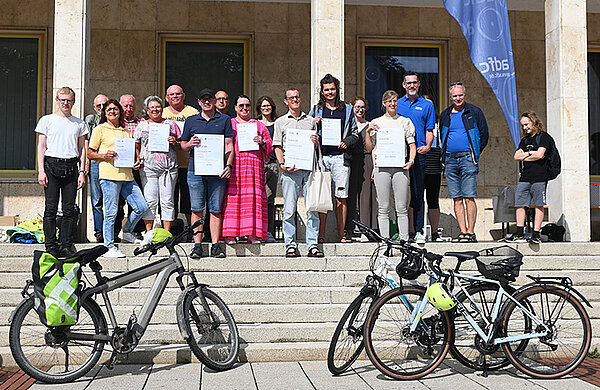 Gruppenfoto mit den Siegern des STADTRADELN vor dem Rathausplatz, im Vordergrund Fahrräder