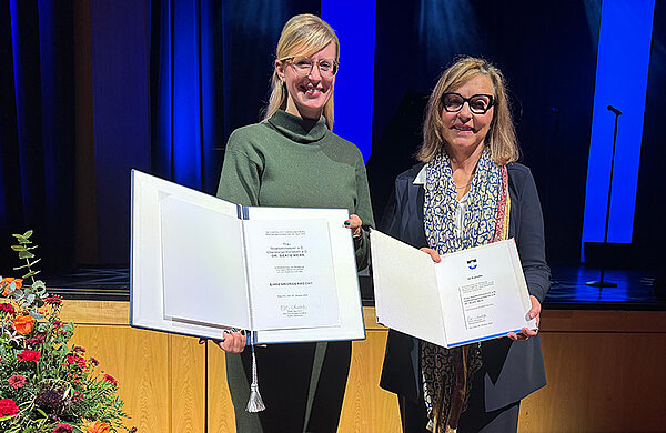 Dr. Beate Merk und Oberbürgermeisterin Katrin Albsteiger halten die Urkunden zum Ehrenbürgerrecht und dem Ehrenring in die Kamera