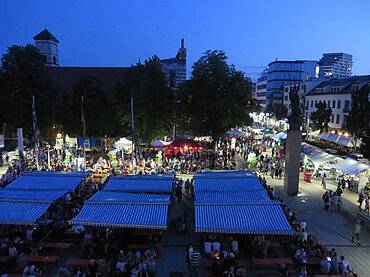 Nachtaufnahme vom Rathausplatz und der Augsburger Straße mit zahlreichen Ständen und Stadtfest-Besuchern
