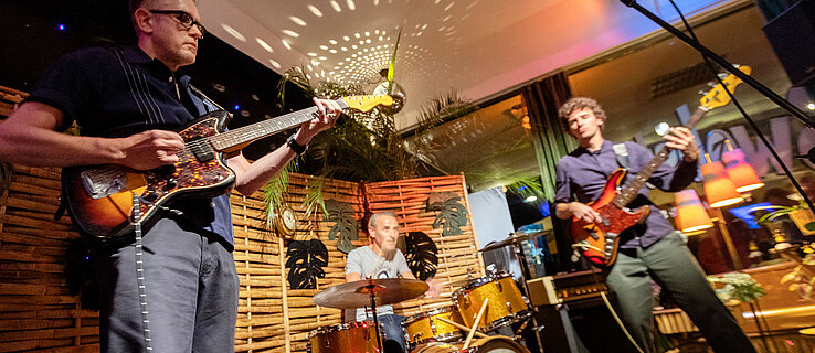 Konzert einer Band mit zwei Gitarristen und einem Schlagzeuger