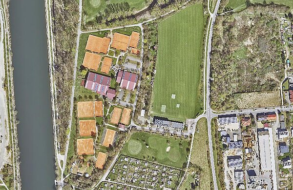 Luftbild des Geländes mit Gebäuden sowie Tennisplätzen nahe der Donau