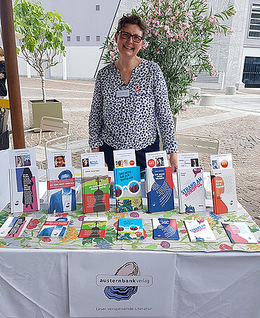 Verlagsleiterin Bettina Deininger vom Austernbank Verlag hinter einem Tisch mit Büchern