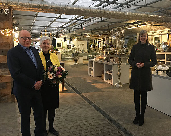 Oberbürgermeisterin Katrin Albsteiger und das Ehepaar Vietzen stehen in der Gärtnerei Vietzen. Frau Vietzen hält einen Blumenstrauß in der Hand.