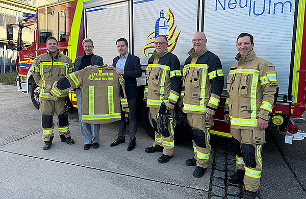 Feuerwehrleute in der neuen Schutzkleidung vor einem Feuerwehrauto