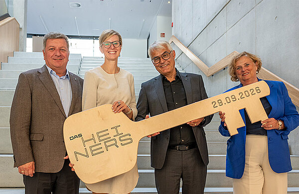Vertreter von Stadt, Bauministerium, der Entwicklungsgesellschaft und der Regierung halten einen großen symbolischen Schlüssel mit der Aufschrift "Das Heiners".