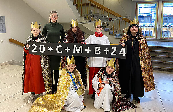 Sechs als Heilige Könige verkleidete Kinder neben Oberbürgermeisterin Katrin Albsteiger und mit einem großen Banner mit dem Segensspruch 20*C+M+B+24