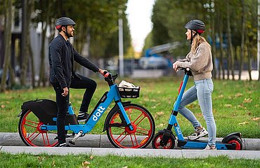 Zwei Personen mit einem E-Tretroller und einem E-Bike der Marke dott