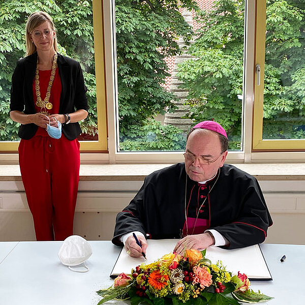Eintrag des Bischofs in das goldene Buch, im Hintergrund Oberbürgermeisterin Katrin Albsteiger