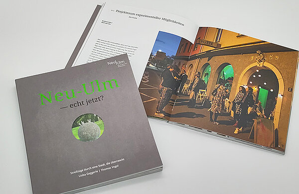 Die Titelseite des Buches "Neu-Ulm - echt jetzt?" und daneben das aufgeschlagene Buch