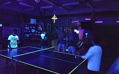 Tischtennisspiel bei Dunkeln und Schwarzlicht
