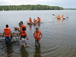 Jugendliche fahren mit Flößen auf einem See