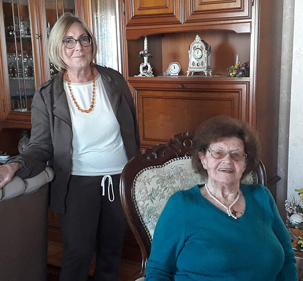 Die Jubilarin sitzend auf einem Stuhl in einem Wohnzimmer, hinter ihr stehend Bürgermeisterin Gerlinde Koch.