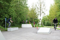Jugendliche mit Skateboards und Bikes auf dem Skateplatz in Pfuhl
