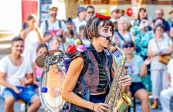 Eine Straßenkünstlerin musiziert vor Publikum auf einem Saxophon