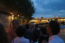 Die Gäste und Gastgeber stehen bei Abenddämmerung vor einer Brücke