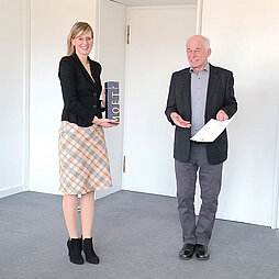 Dr. Bernd Heise hält die Bürgermedaille und die Urkunde in den Händen, daneben Oberbürgermeisterin Katrin Albsteiger mit einer Flasche Champagner in einem Geschenkkarton