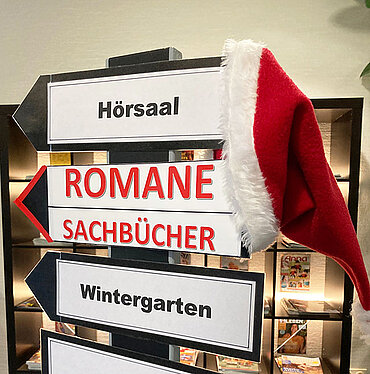 Wegweiser in der Bücherei mit roter Nikolausmütze