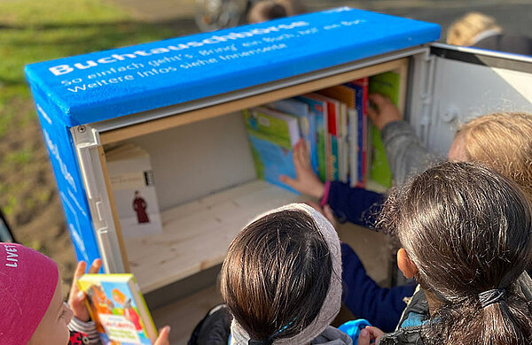 Kinder sellen Bücher in den Schrank.