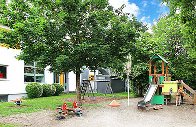 Kita-Garten mit Schaukel, Wippe und Kletterturm mit Rutsche