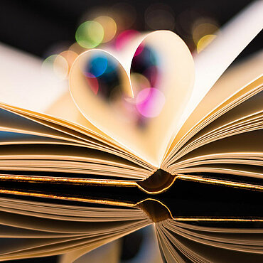 Aufgeschlagenes Buch, die innersten zwei Seiten bilden dabei die Form eines Herzes.