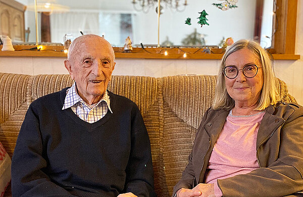 Neu-Ulms dritte Bürgermeisterin Gerlinde Koch und der Jubilar sitzen gemeinsam auf einer Couch.