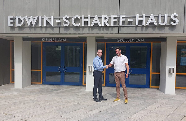 Manfred Weise und Thomas Eder stehen vor dem Edwin-Scharff-Haus und reichen sich die Hand.