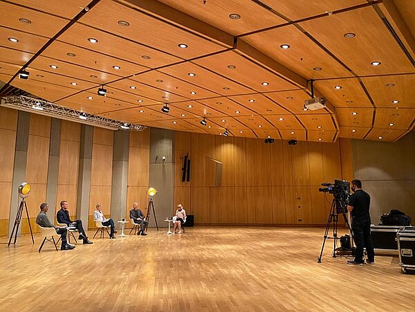 Foto von der Übertragung des Livestreams: Ein Kameramann filmt die Diskussion der Fachleute aus der Verwaltung