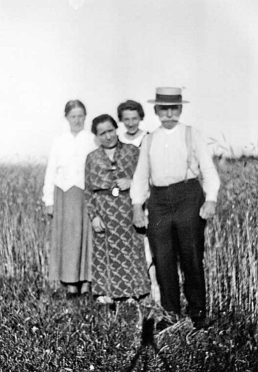 Siegmund Liebermann mit Hut, neben ihm drei Frauen, vor einem Getreidefeld